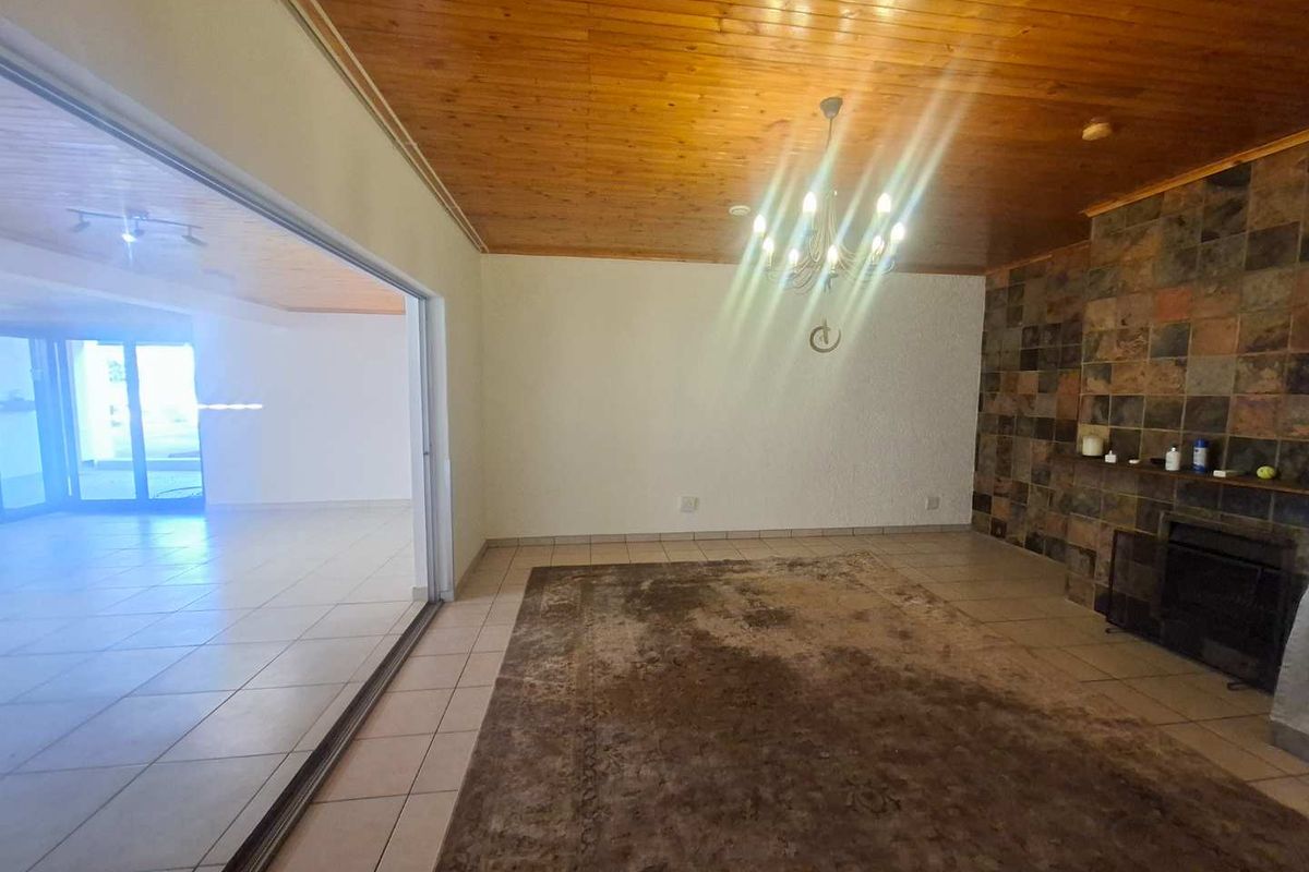 Spacious living room featuring a timber ceiling, slate-tiled fireplace, and large sliding glass doors leading to an adjacent room.