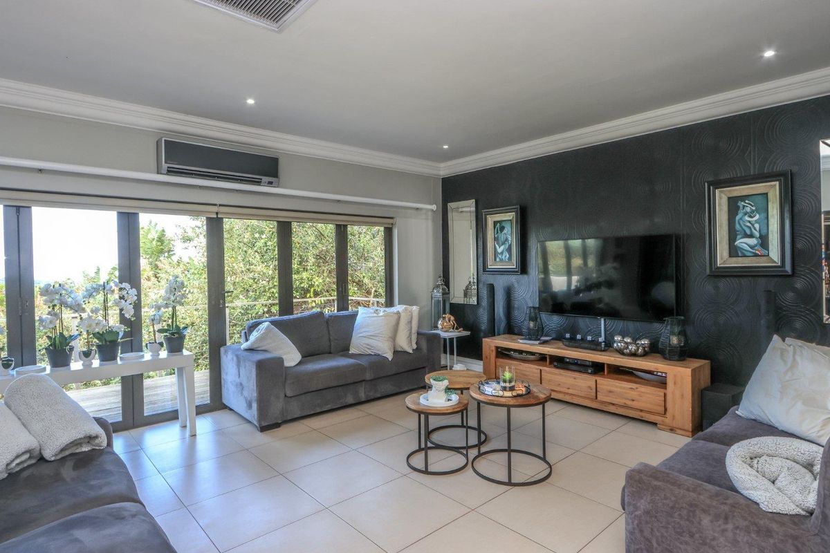 Spacious living room featuring tiled floors, recessed lighting, a split-system air conditioner, and large sliding glass doors providing natural light and outdoor access.