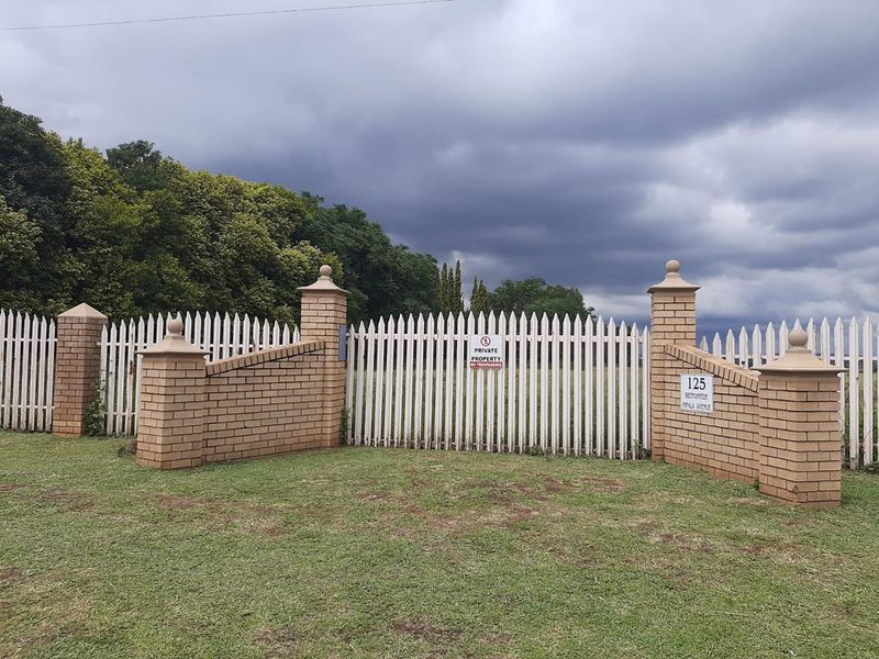 Front view of the agricultural property featuring a secure brick and picket fence boundary with a gated entrance.