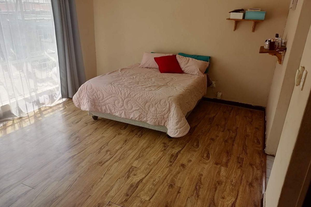 A bedroom featuring laminate flooring, a sliding glass door providing natural light, and wall-mounted shelving units.