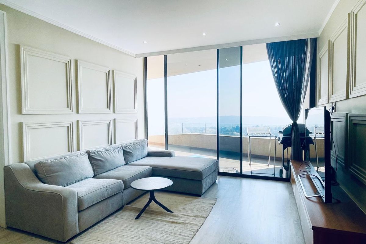 Modern living room featuring elegant wainscoting, recessed lighting, and large sliding glass doors that open onto a balcony with scenic views.