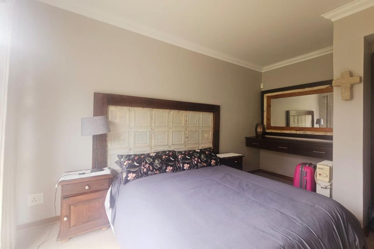 A well-proportioned bedroom featuring neutral wall tones, crown molding, and a built-in floating vanity unit with an integrated mirror.
