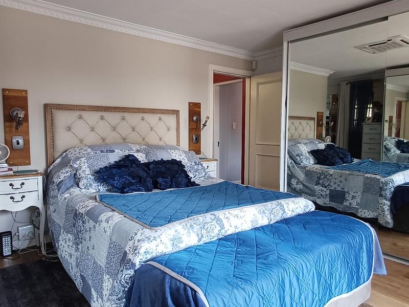 A well-maintained bedroom featuring laminate flooring, crown molding, and a large built-in wardrobe with mirrored sliding doors.