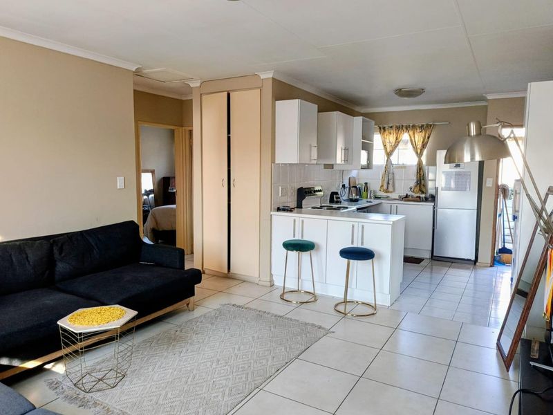 Open-plan living area featuring a functional kitchen with white cabinetry, a breakfast peninsula, and tiled flooring throughout the combined space.