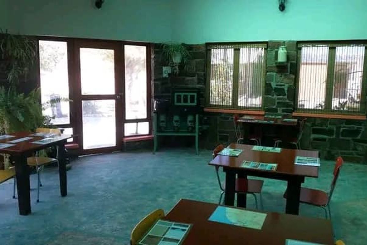 Spacious interior area featuring rustic stone walls, large windows, and concrete flooring, suitable for a dining or communal gathering space.