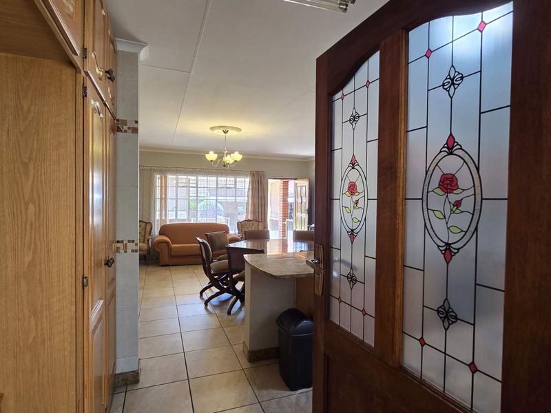 Open plan living and dining area featuring tiled flooring, built-in cabinetry, and a decorative leaded glass door leading into the space.