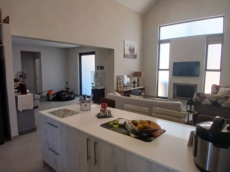 Spacious open-plan living area featuring a modern kitchen island, vaulted ceilings, and a cozy fireplace, creating a bright and airy atmosphere.