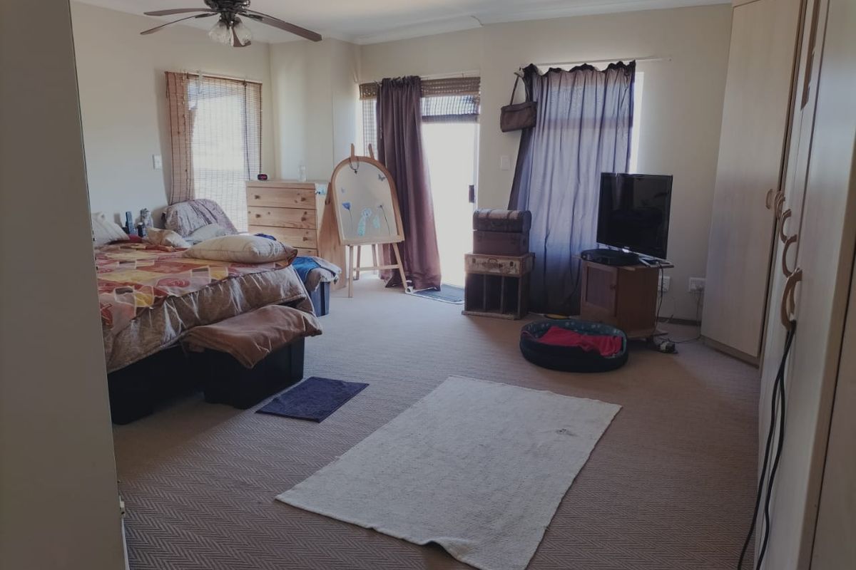 Spacious bedroom featuring neutral carpeting, a ceiling fan, and direct access to an outdoor area through a glass door.