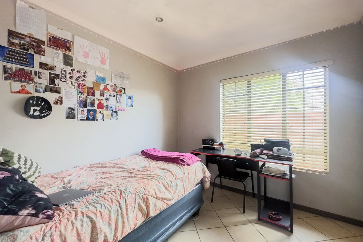 A functional bedroom featuring tiled flooring, recessed ceiling lighting, and venetian blinds, providing a neutral base for personalization.