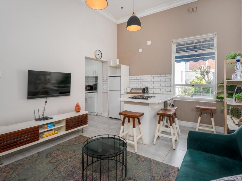 Open-plan living and kitchen area featuring tiled floors, a modern subway tile backsplash, built-in cabinetry, and a gas cooktop island.