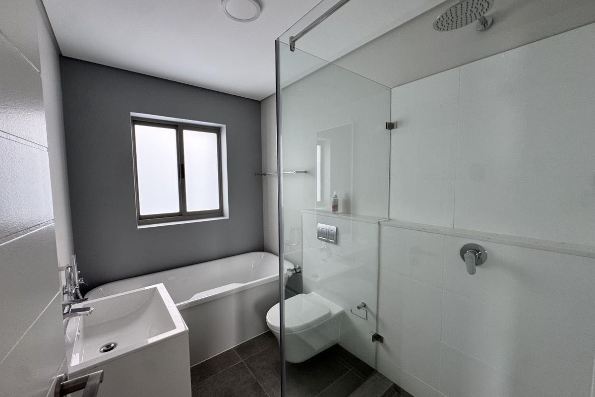 Modern bathroom featuring a sleek freestanding bathtub, a glass-enclosed shower with a rain head, and a wall-mounted toilet with contemporary finishes.