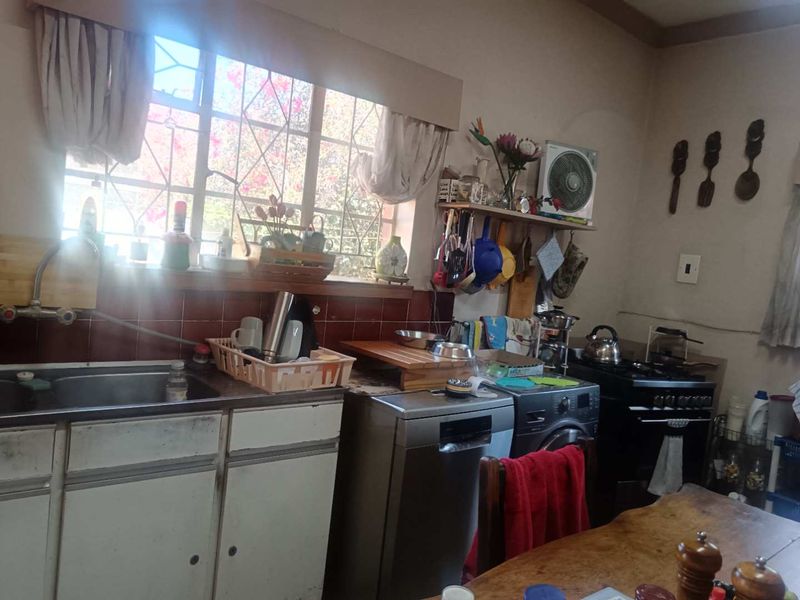 A functional kitchen featuring a stainless steel sink, tiled backsplash, and built-in cabinetry, offering potential for modernization and layout optimization.