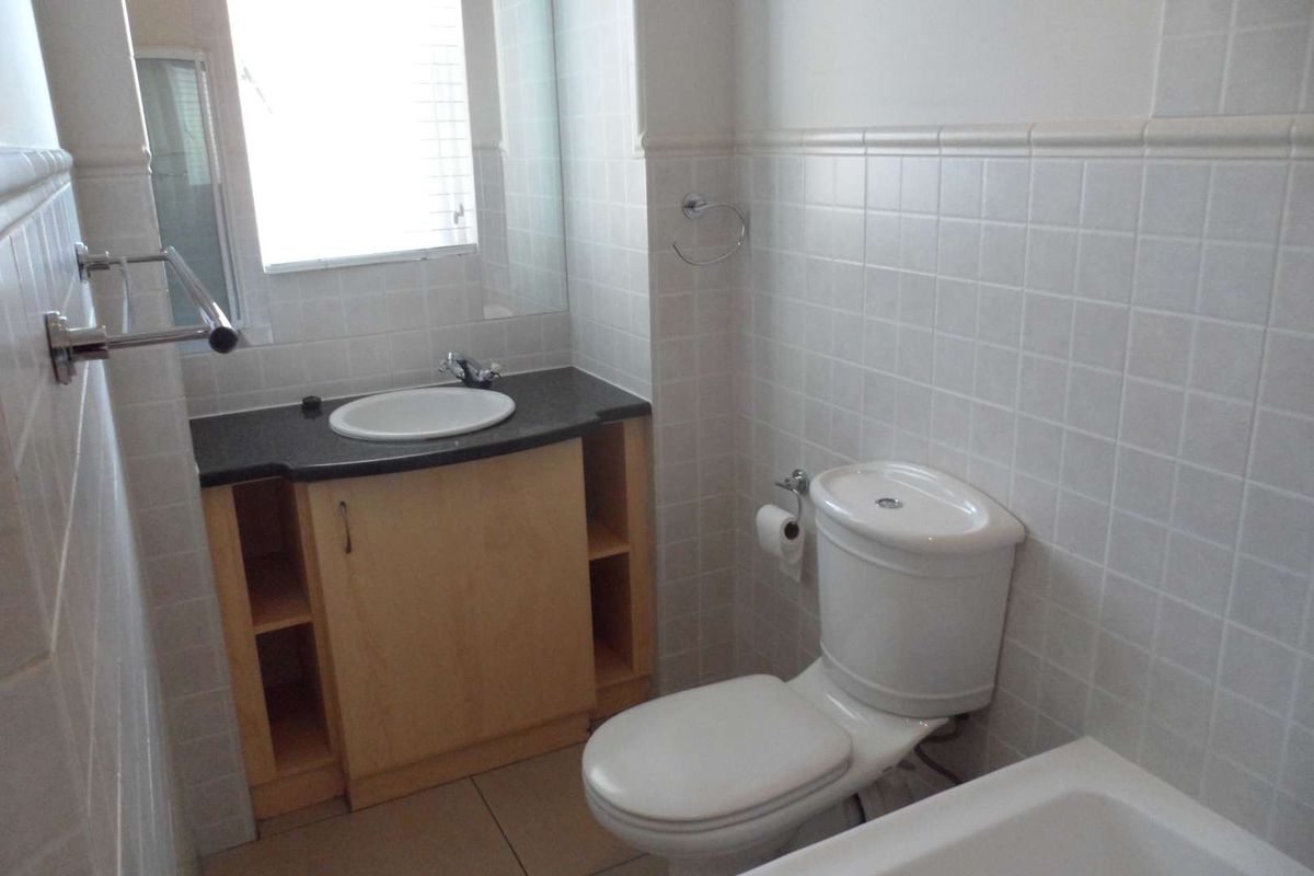 A functional bathroom featuring a vanity cabinet with a drop-in sink, a standard toilet, and tiled wall finishes.