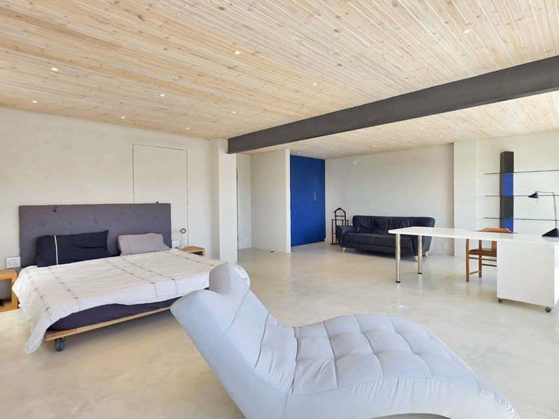 Spacious bedroom featuring a timber-clad ceiling, exposed steel beam, and polished concrete flooring with integrated storage and recessed lighting.