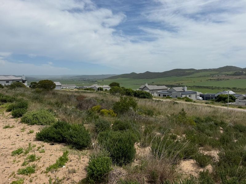 A scenic view overlooking the vacant residential land with surrounding hills and established neighborhood properties in the distance.