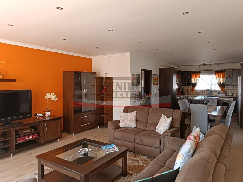Open-plan living and dining area featuring laminate flooring, recessed lighting, and an integrated kitchen with cabinetry and tiled backsplash.
