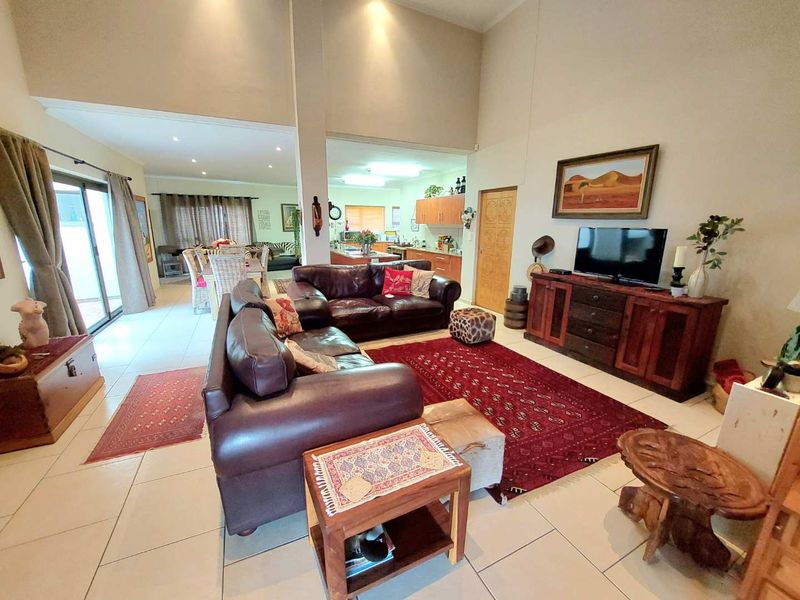 Spacious open-plan living area featuring high vaulted ceilings, tiled flooring, and seamless flow to the dining space and kitchen.