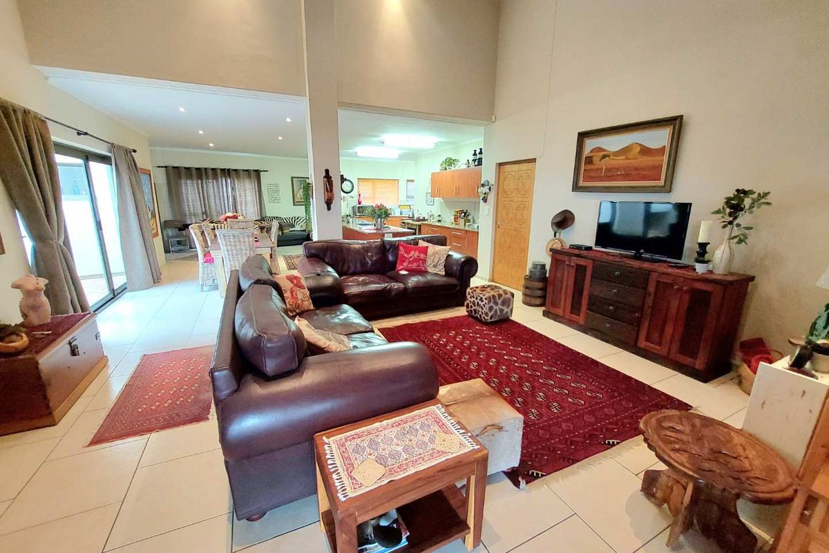 Spacious open-plan living area featuring high vaulted ceilings, tiled flooring, and seamless flow to the dining space and kitchen.