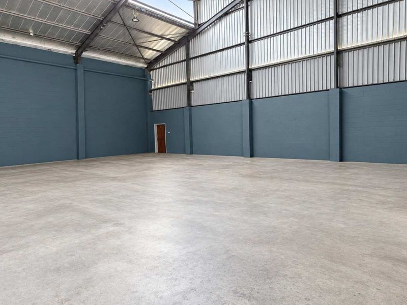 Spacious industrial warehouse unit featuring polished concrete flooring, high exposed steel roof trusses, and freshly painted concrete block walls.