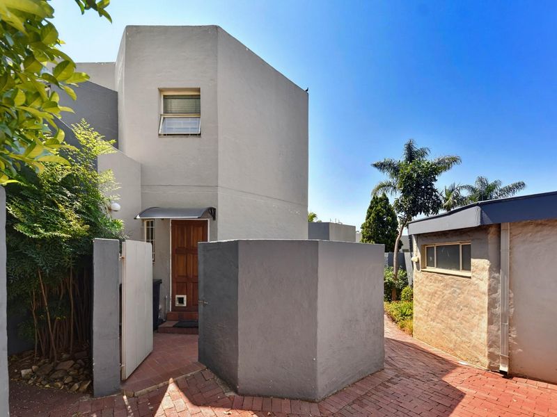 Front entrance area of the townhouse featuring a brick paved pathway, private boundary wall, and timber front door with a built-in pet flap.