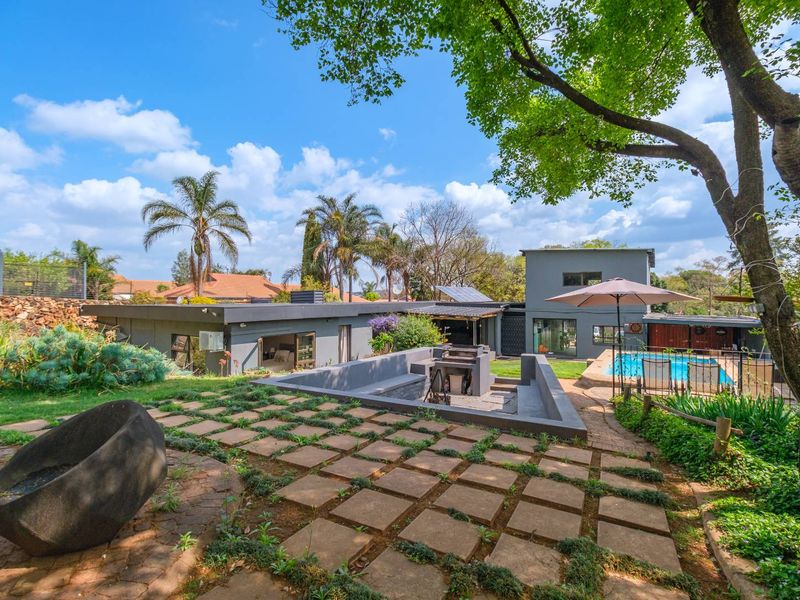 Spacious rear garden featuring a swimming pool, a sunken fire pit area with built-in braai, and well-maintained landscaping.