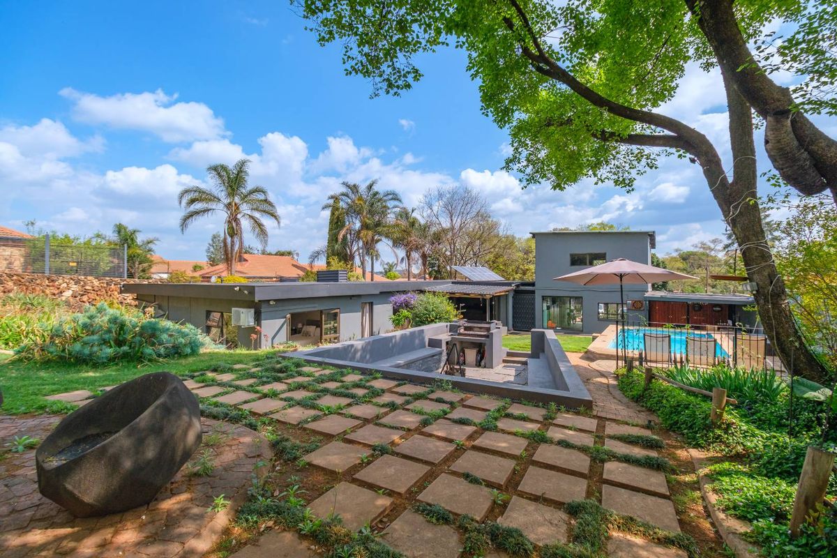 Spacious rear garden featuring a swimming pool, a sunken fire pit area with built-in braai, and well-maintained landscaping.