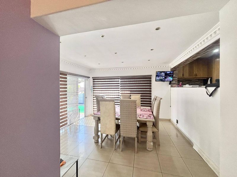 A bright dining area featuring tiled floors, crown molding, recessed lighting, and a sliding glass door providing access to the outdoor area.