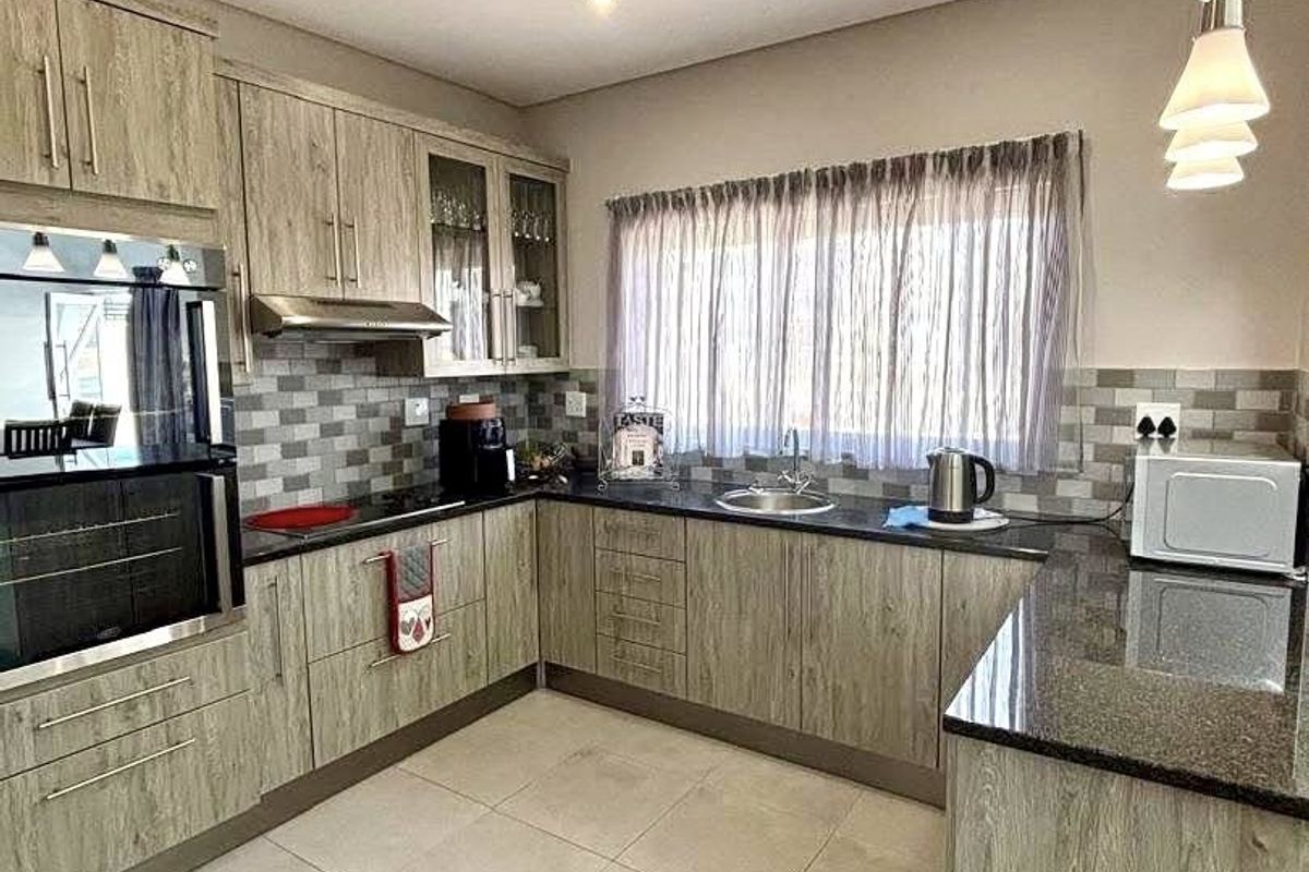 Modern kitchen featuring wood-grain cabinetry, granite countertops, tiled backsplash, built-in oven, and recessed lighting, offering a functional and contemporary cooking space.
