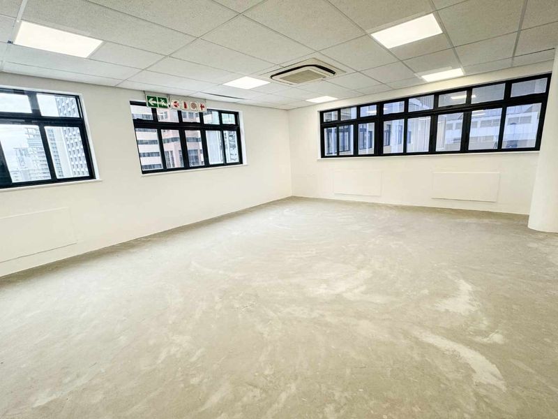A spacious, vacant office suite featuring a suspended ceiling, recessed lighting, ducted air conditioning, and large windows with aluminium frames.