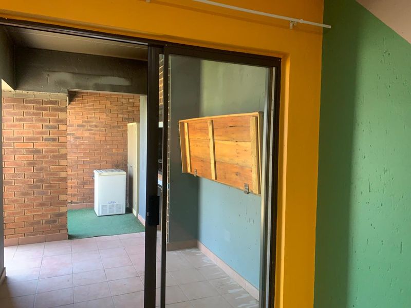 A covered patio area featuring brick walls, tiled flooring, and a built-in braai, offering potential for an outdoor entertainment space.