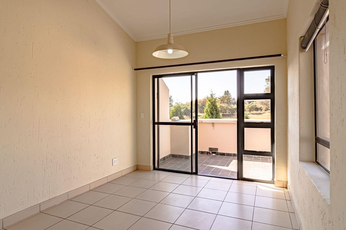 An empty living room featuring tiled flooring, textured walls, and a sliding glass door providing access to an outdoor balcony area.
