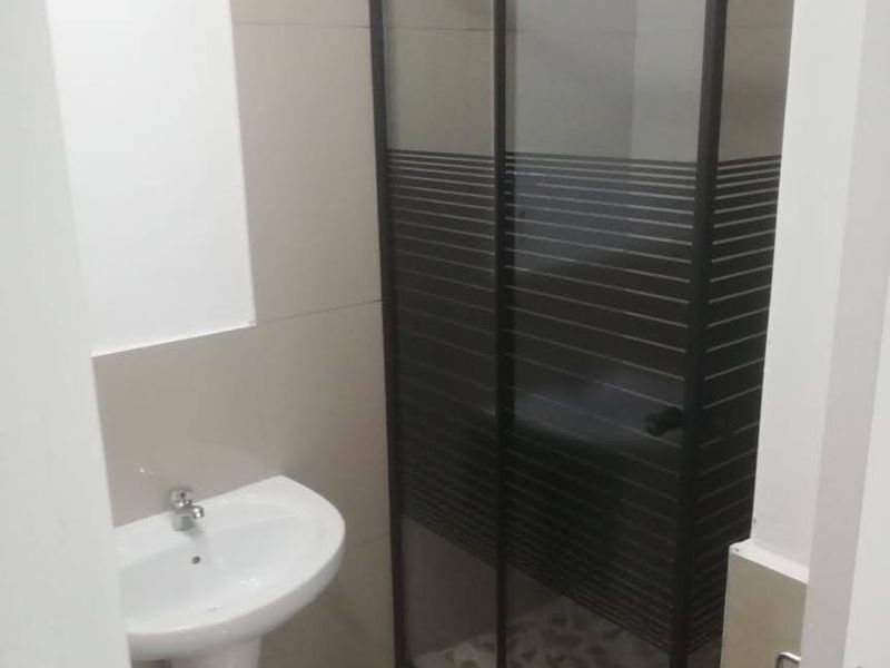 A clean, functional bathroom featuring a pedestal basin and a modern shower enclosure with a glass door.