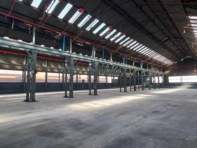 Spacious industrial warehouse featuring a robust steel portal frame, concrete flooring, and extensive skylights providing ample natural light throughout the open floor plan.
