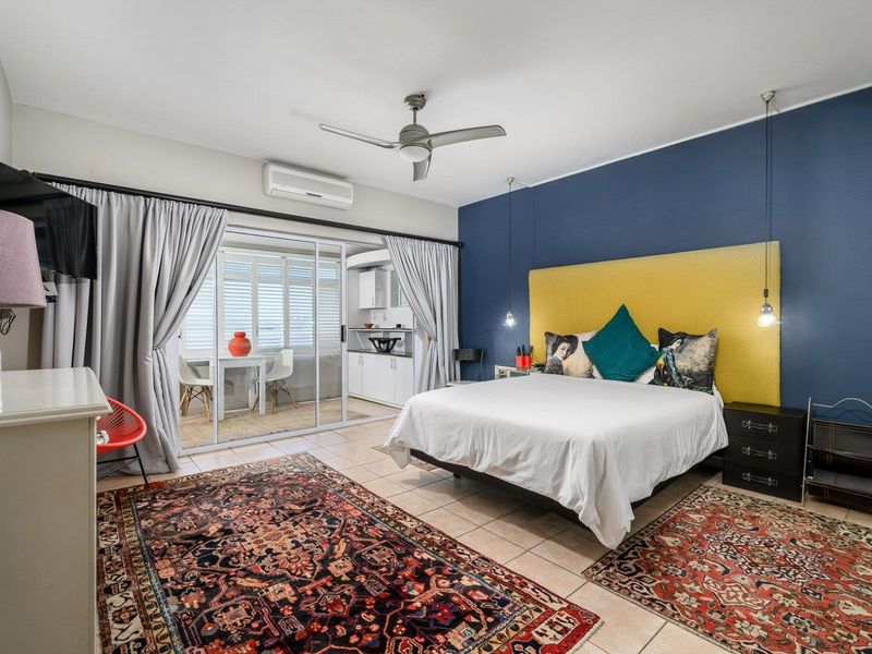 Spacious bedroom featuring tiled flooring, a ceiling fan, split-system air conditioning, and sliding glass doors leading to an enclosed balcony area.