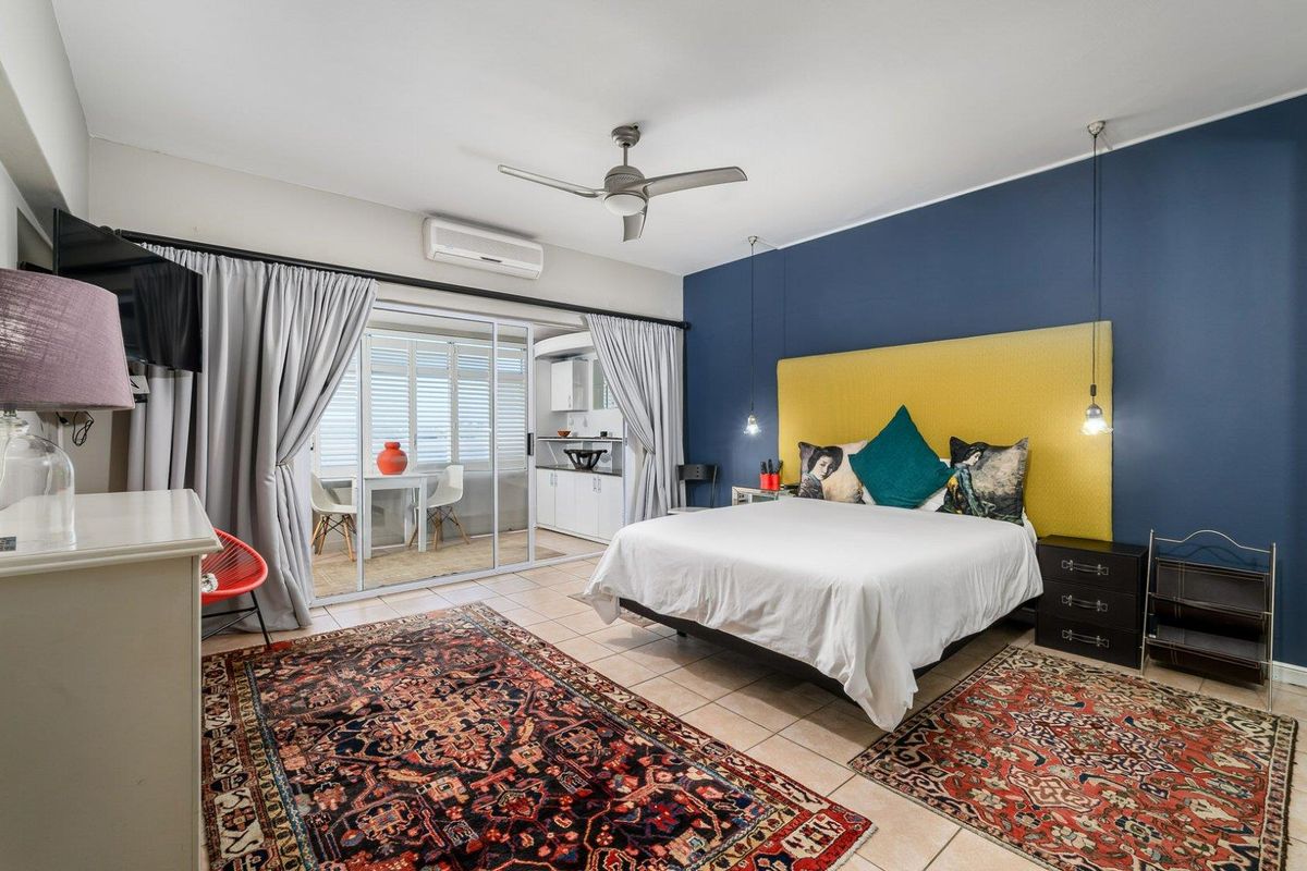 Spacious bedroom featuring tiled flooring, a ceiling fan, split-system air conditioning, and sliding glass doors leading to an enclosed balcony area.