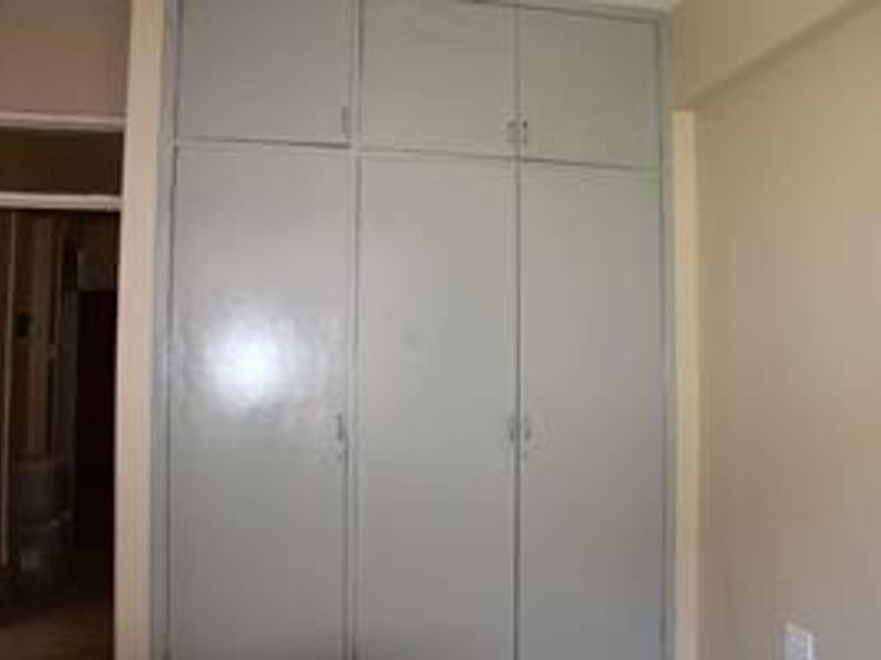 A bedroom featuring floor-to-ceiling built-in cupboards with overhead storage compartments.