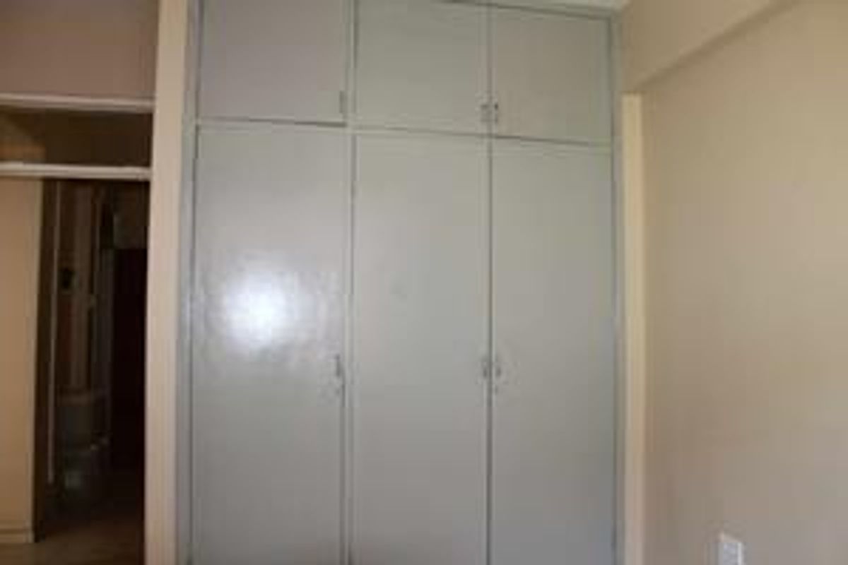 A bedroom featuring floor-to-ceiling built-in cupboards with overhead storage compartments.