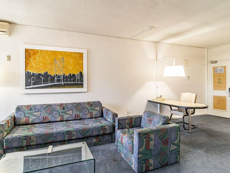A living room area featuring carpeted flooring, a wall-mounted air conditioning unit, and a standard entrance door.