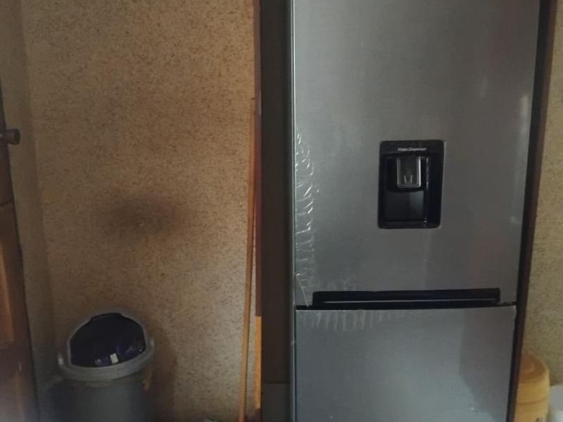 A kitchen corner featuring tiled flooring and built-in cabinetry, showing signs of wear on the wall surfaces.