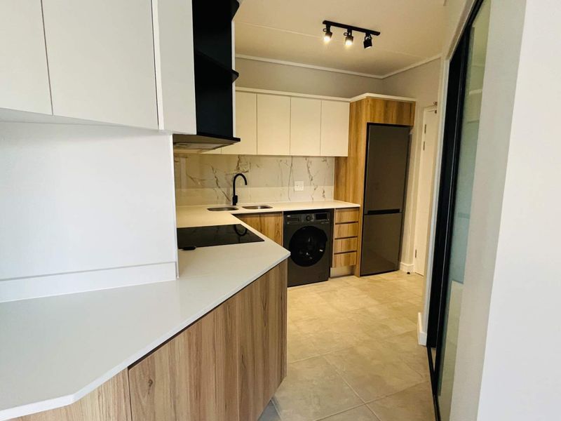 Modern kitchen featuring sleek wood-grain and white cabinetry, stone countertops, marble-look backsplash, and integrated appliances in a clean, contemporary layout.