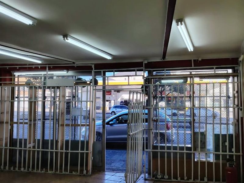 Commercial entry area featuring tiled flooring, fluorescent lighting, and security gates, providing direct access to the street front.
