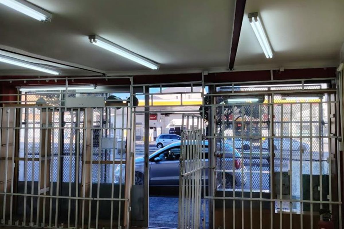 Commercial entry area featuring tiled flooring, fluorescent lighting, and security gates, providing direct access to the street front.