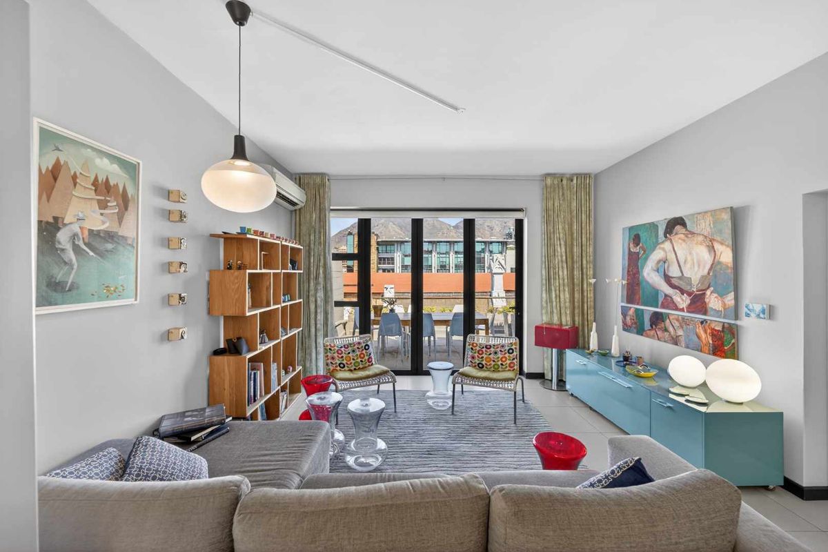 A bright and well-maintained living room featuring tiled flooring, a split-system air conditioner, and large sliding glass doors leading to an outdoor balcony area.