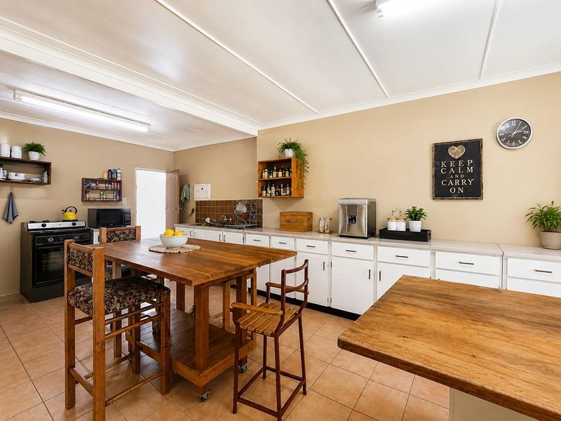 A functional kitchen featuring white cabinetry, tiled flooring, and a freestanding stove, offering ample counter space and a practical layout.
