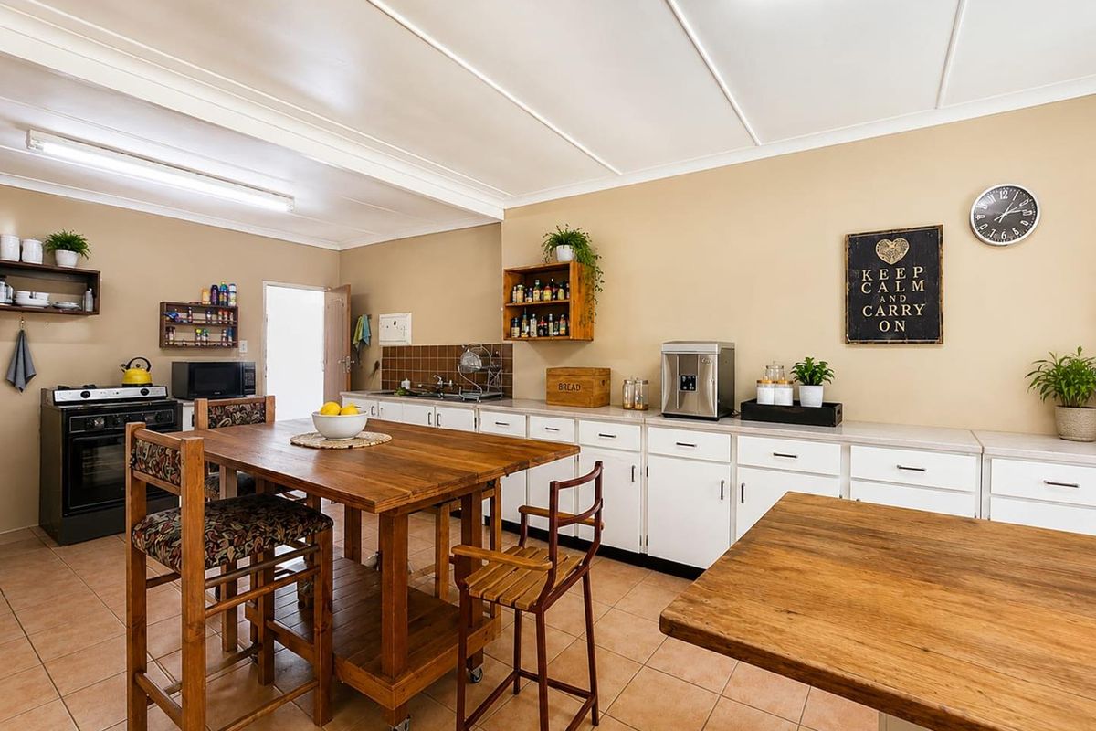 A functional kitchen featuring white cabinetry, tiled flooring, and a freestanding stove, offering ample counter space and a practical layout.