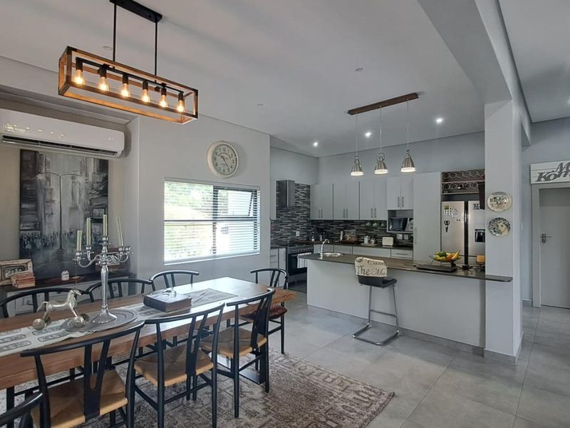 Spacious open-plan living and dining area featuring a modern kitchen with a central island, sleek cabinetry, and neutral tiled flooring throughout.