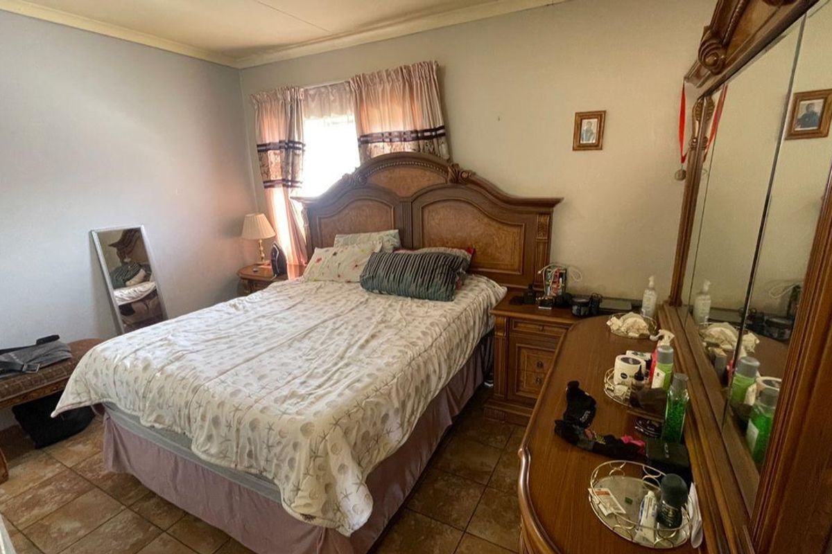 A standard bedroom featuring tiled flooring and a window with curtain fixtures.