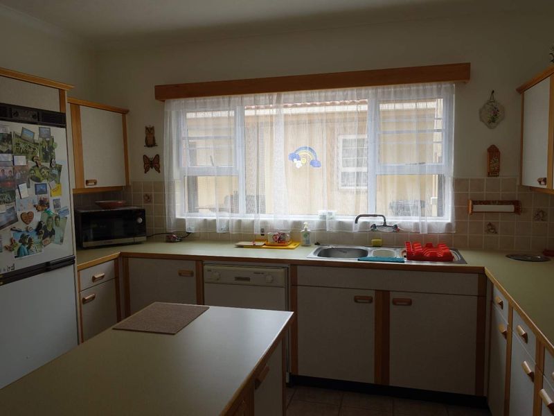 A functional kitchen featuring laminate countertops, double bowl sink, tiled backsplash, and ample built-in cabinetry with an integrated dishwasher.
