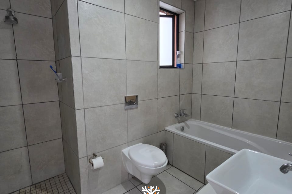 Modern bathroom featuring large format grey wall tiles, a wall-mounted toilet, a built-in bathtub, and a separate walk-in shower area.