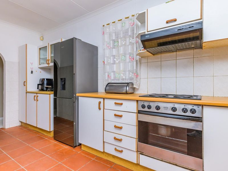 A functional kitchen featuring built-in cabinetry, a gas hob with extractor fan, built-in oven, and tiled flooring.